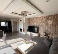 Nappali a családi házban kanapéval, TV-vel és kandallóval, fa dekorációjú padlóval.