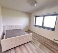 Hálószoba családi házban, ággyal és fa dekorációjú padlóval.