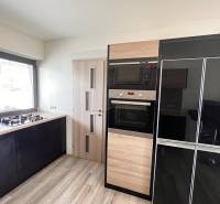 Konyha családi házban gáz tűzhellyel és háztartási gépekkel, fa mintázatú padlóval.