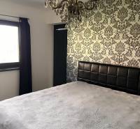 Hálószoba családi házban dekoratív tapétával és csillárral. Az enteriőr dizájn szimfóniája.