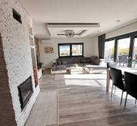 Családi ház belső tere kanapéval, kandallóval és fa dekorációjú padlóval.