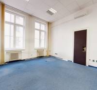 Iroda belső tér kék szőnyeggel, fehér falakkal és nagy ablakokkal.