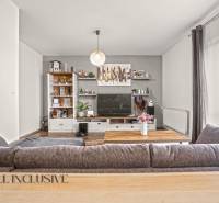 Nappali egy kétszobás lakásban fa hatású padlóval és nagy kanapéval.