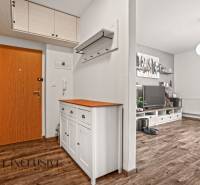 Előszoba egy kétszobás lakásban, fa dekor padlóval és fehér bútorokkal.