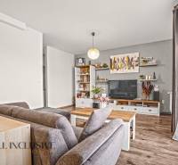 Nappali egy kétszobás lakásban, fa dekoros padlóval, kényelmes ülőgarnitúrával és dekorációkkal.