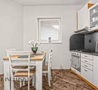 Konyha egy kétszobás lakásban étkezőasztallal és fa dekorációjú padlóval.