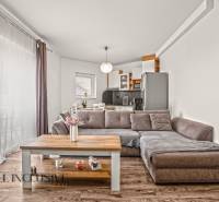 Nappali egy kétszobás lakásban kanapéval, konyhapulttal és fa dekorációjú padlóval.