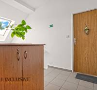 Belépés egy kétszobás lakásba, fa szekrénnyel és egy virággal a fapadlón.