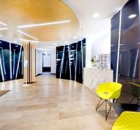 Irodai recepció fa dekorációjú padlóval és zöld növényekkel a falon.