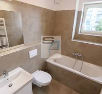 Fürdőszoba egy kétszobás lakásban káddal, mosdóval, tükörrel és ablakkal.