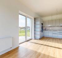 Konyha és nappali rész egy 3 szobás lakásban nagy ablakokkal és kilátással a zöldre.