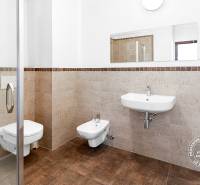 Fürdőszoba egy kétszobás lakásban WC-vel, bidével és zuhanyzóval, csempékkel burkolva.