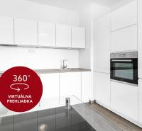 Konyha egy kétszobás lakásban fehér szekrényekkel, sütővel és fa dekoros padlóval.