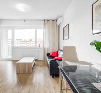 Nappali kanapéval, asztallal és fa dekor padlóval egy kétszobás lakásban.