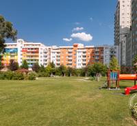 Játszótér mászókákkal, füves terület és lakóépületek a Bosákova utcában.