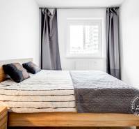 Hálószoba ággyal, éjjeliszekrénnyel és ablakkal egy kétszobás lakásban.