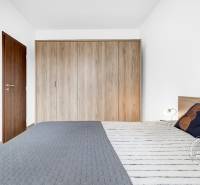 Hálószoba egy kétszobás lakásban, szekrénnyel és franciaággyal, fa mintázatú padlóval.