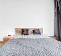 Világos hálószoba ággyal, gardróbszekrénnyel és fa dekorációjú padlóval egy kétszobás lakásban.