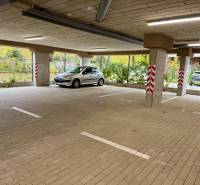 Tágas parkolás a Sadová utcai garázsokban Szenicén, autóval és oszlopokkal.