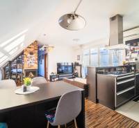 Konyha televízióval, kandallóval és fa hatású padlóval egy kétszobás lakásban.