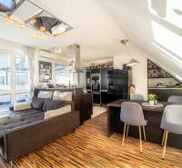 Nappali konyhával egy kétszobás lakásban, fa hatású padlóval és kényelmes kanapéval.