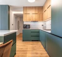 Konyha egy háromszobás lakásban, fa dekor padlóval és zöld szekrényekkel.