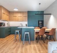 Konyha egy háromszobás lakásban fa dekor padlóval és étkezőasztallal.