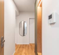 A háromszobás lakás folyosóján van egy tükör és fa dekorációjú padló.