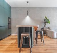 Konyha háromszobás lakásban szigettel, fém székekkel és fa mintázatú padlóval.