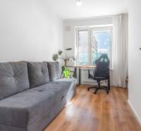 Világos szoba kanapéval, irodai székkel, asztallal és fa dekorációjú padlóval.