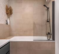 Fürdőszoba káddal, zuhanyfallal és dekoratív csempékkel egy háromszobás lakásban.