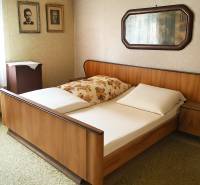 Hálószoba fa ággyal, fényképekkel a falon és tükörrel egy családi házban.