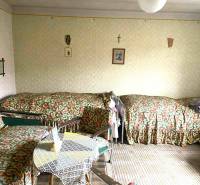 Egy családi ház szobája három ággyal és egy asztallal, dekorokkal burkolva.