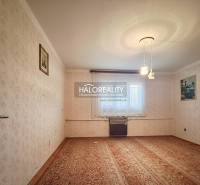 Nappali egy családi házban szőnyeggel, tapétákkal és fali képekkel.