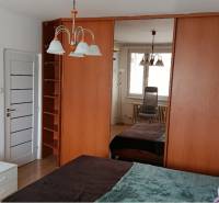 Hálószoba egy egyszobás lakásban nagy tükrös szekrénnyel és csillárral.