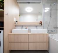 Fürdőszoba egy háromszobás lakásban két mosdóval, tükörrel és káddal.