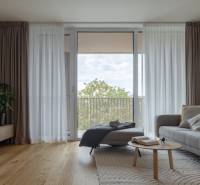 Nappali kanapéval, fa dekoros padlóval és nagy ablakkal egy háromszobás lakásban.