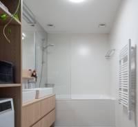 Fürdőszoba egy háromszobás lakásban káddal, mosdóval, polccal és mosógéppel.