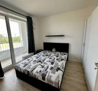 Hálószoba egy kétszobás lakásban, ággyal, szekrénnyel és erkéllyel, fa dekorációjú padlóval.