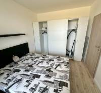 Hálószoba beépített szekrénnyel, ággyal és fa dekoros padlóval egy kétszobás lakásban.