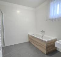 Fürdőszoba családi házban, fa dekorral ellátott káddal és fehér csempékkel.