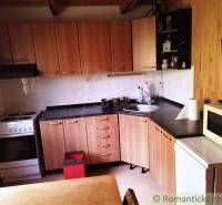 Konyha egy fahatású padlóval rendelkező házikóban, főzőlappal és mikrohullámú sütővel.