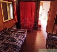 Kétágyas faház belső tér, piros szekrénnyel és geometriai mintás szőnyeggel.