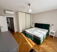 Hálószoba ággyal, szekrénnyel és fa dekorációjú padlóval egy háromszobás lakásban.