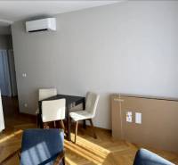 Étkező sarok asztallal, székekkel és fa dekorációjú padlóval egy háromszobás lakásban.