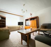 Nappali a családi házban kanapékkal, szekrényekkel és asztallal, szőnyeggel a padlón.