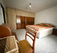 Hálószoba családi házban szőnyeggel, ággyal és szekrénnyel.