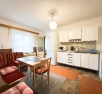 Konyha családi házban világos bútorokkal, étkezőasztallal és ülőhellyel.