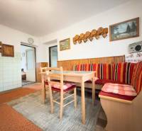 Családi ház étkezője sarokpadokkal, fa dekorációval és dekoratív képekkel a falon.