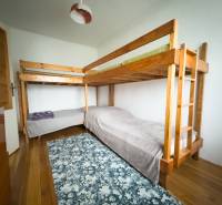 Emeletes ágy egy családi házban, fa mintás padlóval és mintás szőnyeggel.